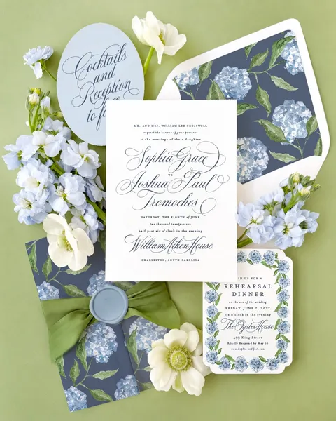 Wedding invitation suite by Jessica Hinton of Empress Stationery, featuring Mozart Script by Blessed Print, blue hydrangea artwork and green ribbon.