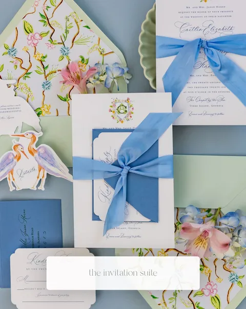 Blue and green floral wedding invitation suite by Claire Hodges Weddings featuring La Rumba calligraphy, patterned envelope liners and blue ribbon.
