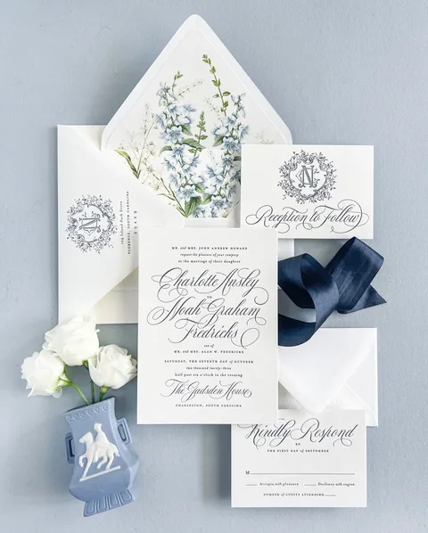 Blue and white wedding invitation suite by Empress Stationery with Mozart Script calligraphy by Blessed Print, a floral envelope liner and navy ribbon.