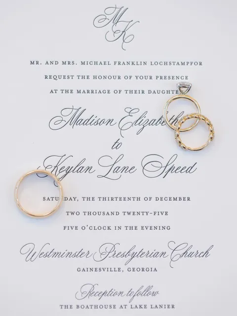 Classic white wedding invitation by Paper Daisies Stationery featuring Juliette calligraphy and a monogram, styled with gold rings. Photograph by Jacqueline Aleace Photography.