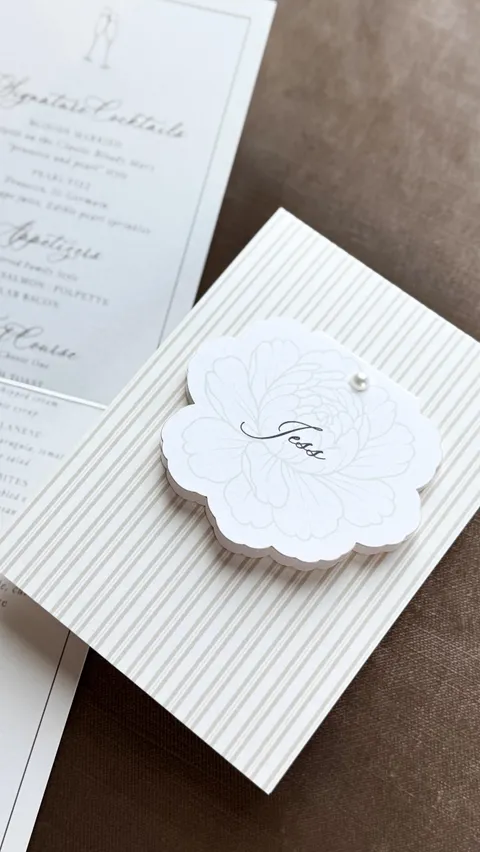 Wedding stationery video cover by Glow Paper Company with La Rumba calligraphy and a scalloped floral seal on a striped envelope.