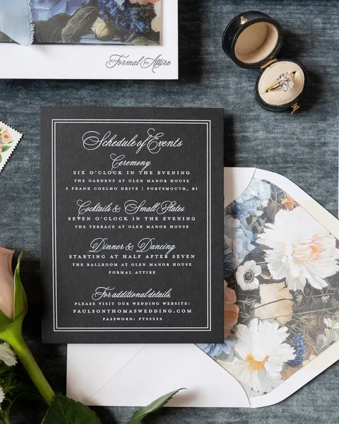 Black wedding weekend schedule by Banter & Charm featuring white Juliette headings, alongside a floral envelope liner and coordinating stationery.
