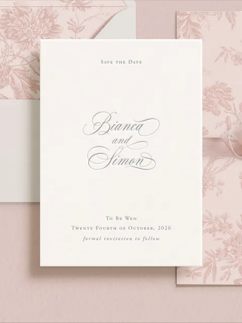 Minimal white Elyssian save-the-date card by Ivory & Stone with Juliette calligraphy, displayed over a pink botanical envelope liner.