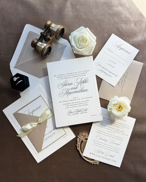 Classic white wedding stationery by Glow Paper Co. featuring black Juliette calligraphy, a vellum wrap, cream ribbon and white roses.