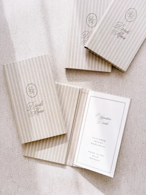 Striped fabric wedding menu folios by Aileen Fretz of Plume with monogrammed covers and Juliette calligraphy on the menu inside.