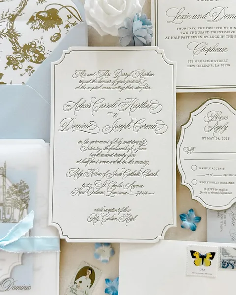 Shaped letterpress wedding invitation by Amber LeBlanc Studio featuring Juliette calligraphy, styled with pale blue envelopes, botanical artwork and vintage stamps.